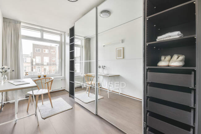 Gran armario con espejos situado en habitación espaciosa diseñada en estilo minimalista en piso nuevo - foto de stock