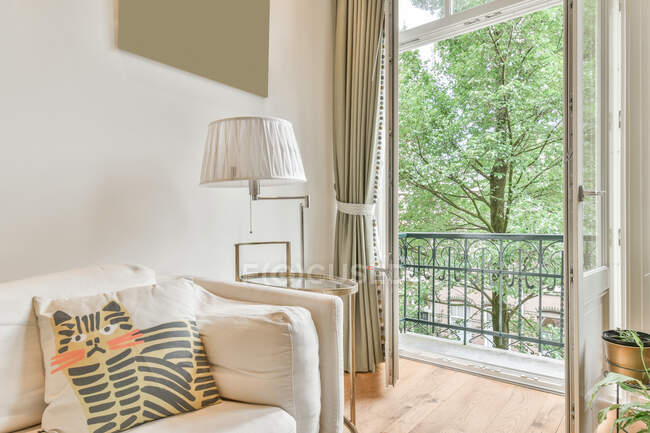 Интерьер гостиной в классическом стиле с удобным диваном рядом с окнами в светлых просторных апартаментах — стоковое фото