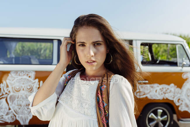 Красивая брюнетка в летней одежде стоит у фургона и смотрит в камеру. — стоковое фото