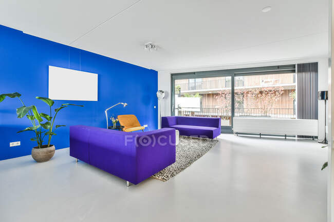 Diseño creativo de la habitación espaciosa con sofás y silla en la alfombra contra el radiador y la ventana en casa - foto de stock