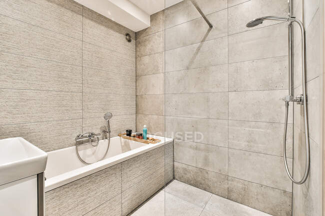 Modernes Duschbad-Interieur mit Badewanne und grau gefliester Wand gegen Waschbecken im Leuchtturm — Stockfoto