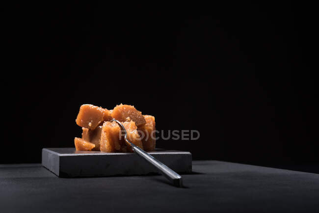 Gourmet quince jelly paste in ceramic plate on black background with spoon — Stock Photo