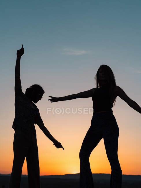 Silhuetas de um casal dançando na natureza enquanto o sol se esconde nas montanhas — Fotografia de Stock