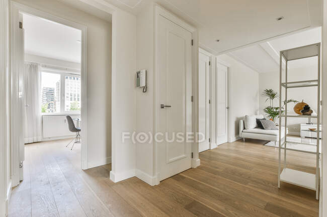 Espaçoso corredor de luz com piso de madeira localizado entre sala de estar e escritório em casa no apartamento moderno — Fotografia de Stock