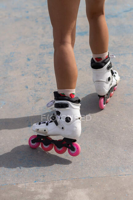 Schnuppern anonyme Frauenbeine in weißen Rollerblades mit rosa Rädern, die auf Betonpflaster im Skatepark stehen — Stockfoto