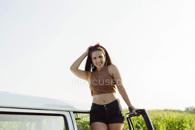 Schöne und glückliche Brünette steht an einem sonnigen Tag auf einem Lieferwagen — Stockfoto