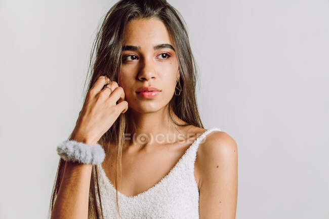 Reflective young Hispanic woman with makeup looking away on light background — Stock Photo