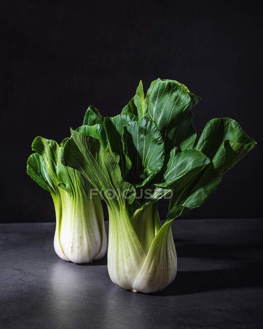 Verdura sana de hoja de col bok choy fresca colocada sobre una mesa negra sobre fondo oscuro - foto de stock