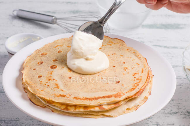 Metal spoon on keto crepe cake with erythritol sweetener and frosting made of cream cheese and whipped cream served on table — Stock Photo