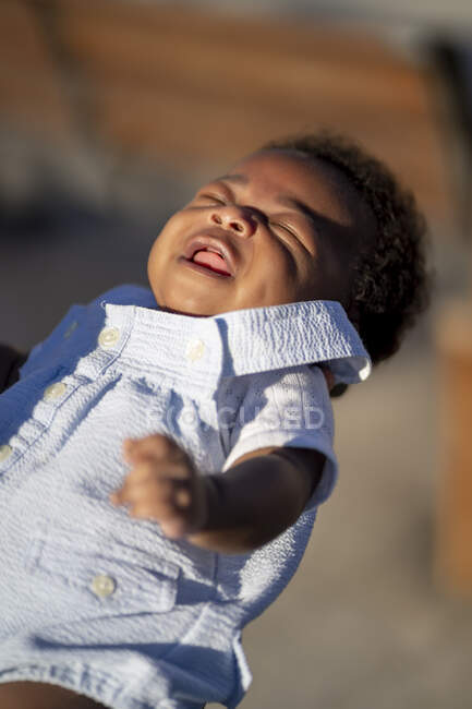 Attento padre ritagliato irriconoscibile in piedi e abbracciando il piccolo bambino afroamericano con i capelli ricci sulla strada nella giornata di sole — Foto stock