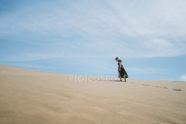 Full body vista posteriore della femmina a piedi nudi in abito passeggiando su dune sabbiose nel deserto — Foto stock