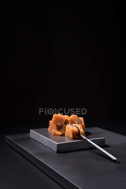 Gourmet marmelo pasta de geleia em placa de cerâmica sobre fundo preto com colher — Fotografia de Stock