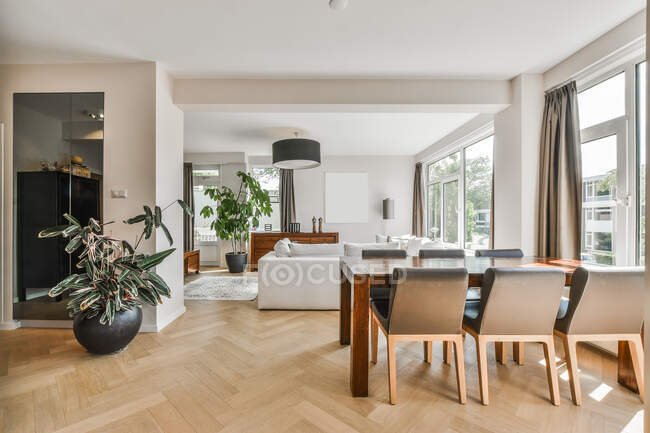 Design criativo de jantar espaçoso e sala de estar interior com sofá e mesa em parquet sob lustre em casa — Fotografia de Stock