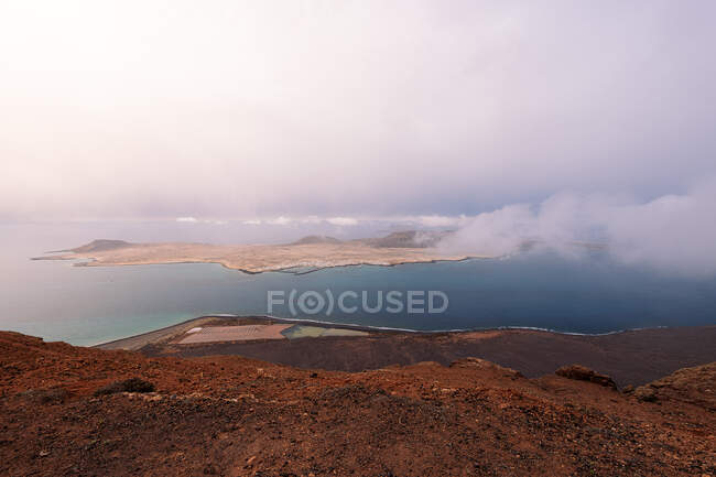 Pintoresca vista de la Isla Graciosa con montes volcánicos entre el Estrecho de Río al atardecer en Teguise Lanzarote España - foto de stock