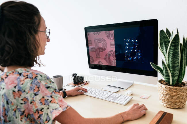 Зверху жінка-дизайнер використовує сучасний комп'ютер під час роботи в сучасному офісі — стокове фото