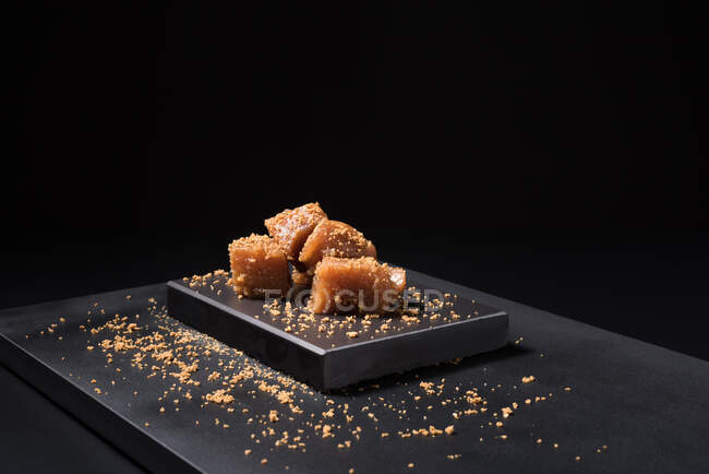 Жирна паста з желе в керамічній тарілці, посипана насінням кунжуту на чорному фоні — стокове фото