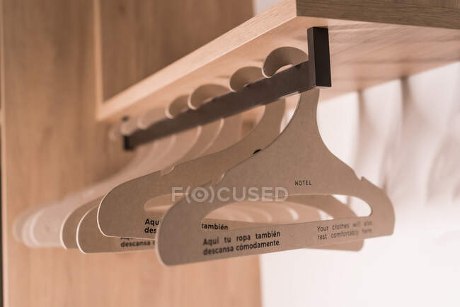 Fila de cabides de metal pendurados sob prateleira no armário de madeira no quarto do hotel — Fotografia de Stock
