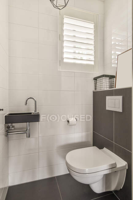 WC blanco y lavabo montado en las paredes cerca del espejo en el cuarto de baño contemporáneo luz - foto de stock