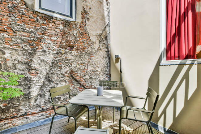Сходи з металевими поручнями прикрашені зеленою рослиною, розташованою на терасі зі стільцями за столом біля сучасного будинку з вікном — стокове фото