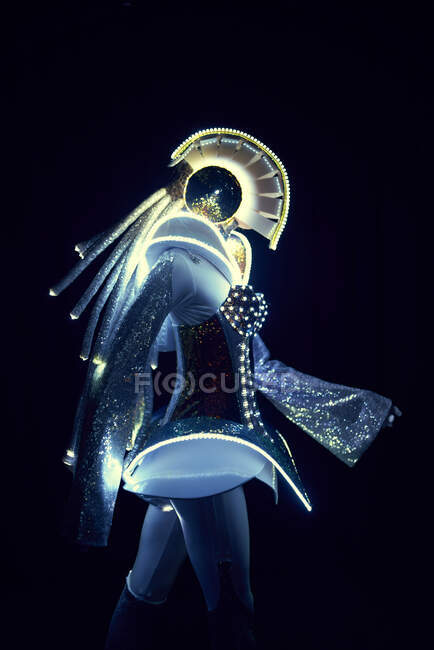Вид сбоку неузнаваемого человека в футуристическом светодиодном костюме космического персонажа с светящимися неоновыми огнями на черном фоне в студии — стоковое фото