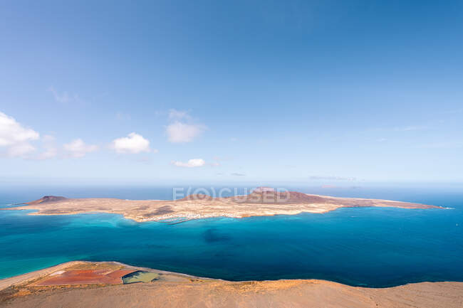 Pintoresca vista de la Isla Graciosa con montes volcánicos entre el Estrecho de Río al atardecer en Teguise Lanzarote España - foto de stock