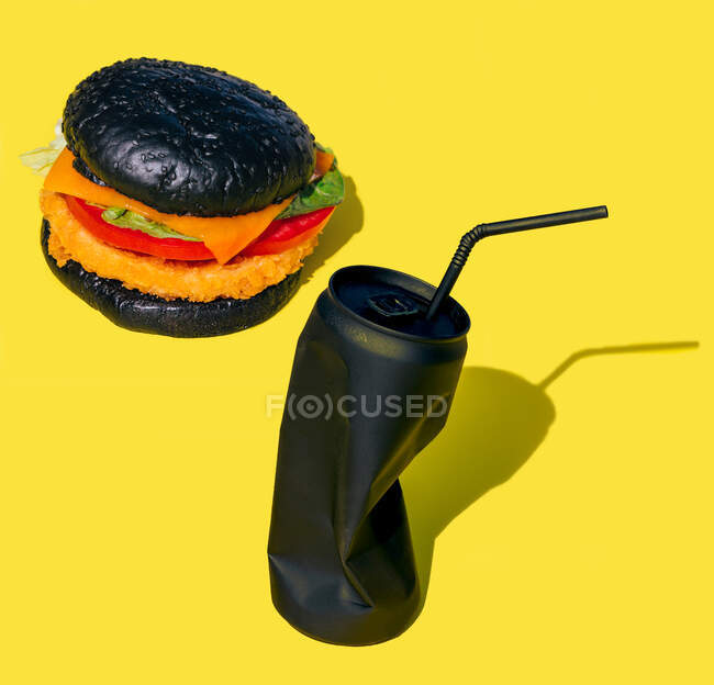 Frischer Burger mit Gemüse in der Nähe einer schwarzen Dose Limonade mit Stroh vor gelbem Hintergrund — Stockfoto