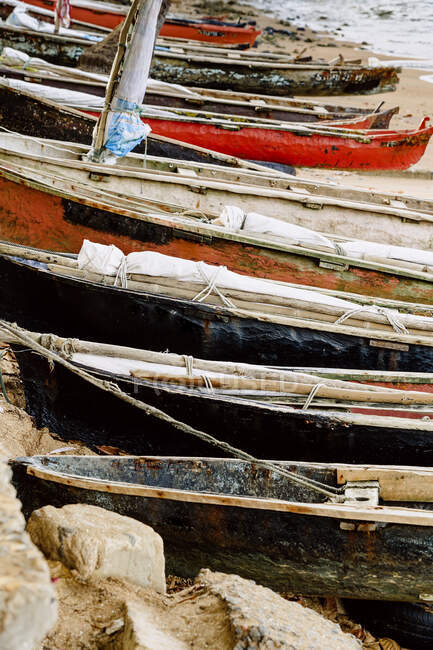 Fila di barche di legno invecchiate ormeggiate sulla spiaggia sabbiosa dell'oceano sull'isola So Tom e Prncipe nella giornata di sole — Foto stock