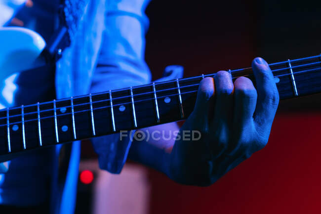 Cropped guitarrista feminina irreconhecível tocando guitarra acústica no clube de luz — Fotografia de Stock