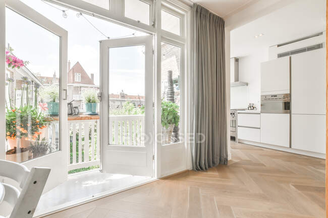 Balkon geöffnete Fenster in geräumiger Küche mit weißen Möbeln und modernen Geräten in heller Wohnung — Stockfoto