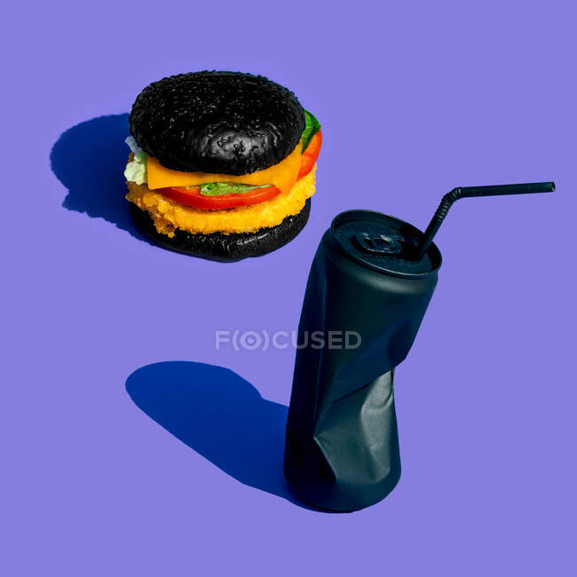 Frischer Burger mit Gemüse in der Nähe einer schwarzen Dose Limonade mit Stroh vor fliederfarbenem Hintergrund — Stockfoto