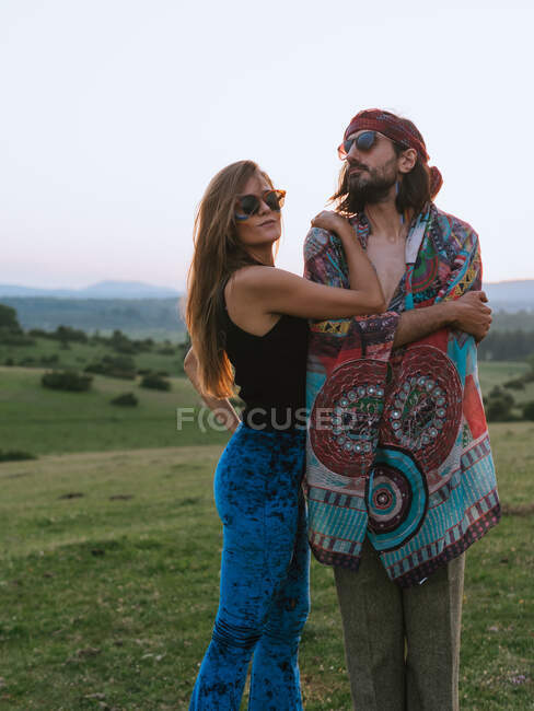 Hippie couple hugging with rainbow painted on their faces while looking away — Stock Photo
