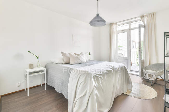Interior of contemporary bedroom with soft bed and wooden bedside table designed in minimal style in flat — Stock Photo