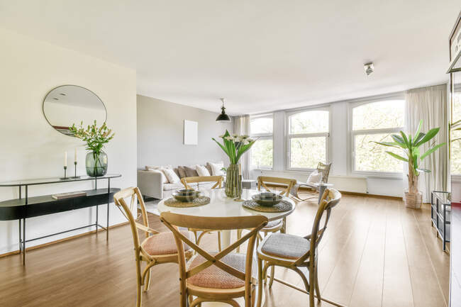 Intérieur du salon spacieux avec mobilier gris et parquet beige avec table à manger dans l'appartement dans un style minimal — Photo de stock