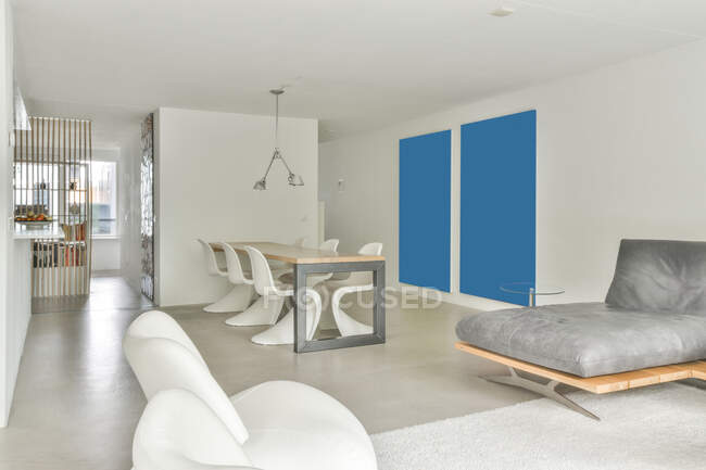 Design creativo degli interni della sala da pranzo con tavolo e sedie contro divano e poltrone su tappeto a casa — Foto stock