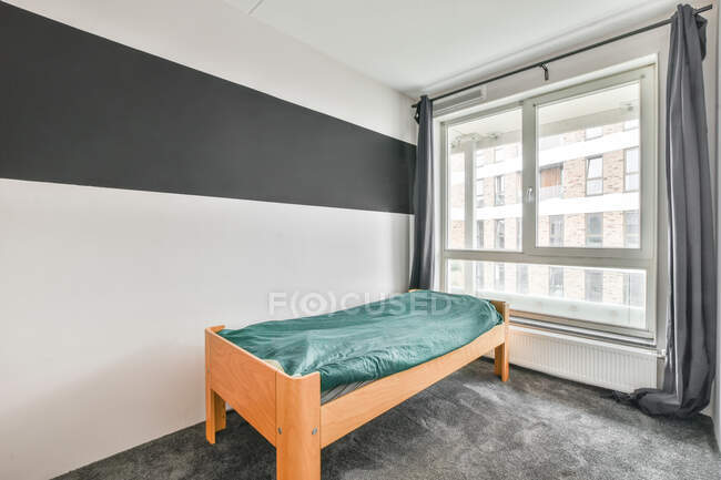 Innengestaltung des Schlafzimmers mit heller Wand und grauem Boden und Einzelbett mit türkisfarbener Decke — Stockfoto