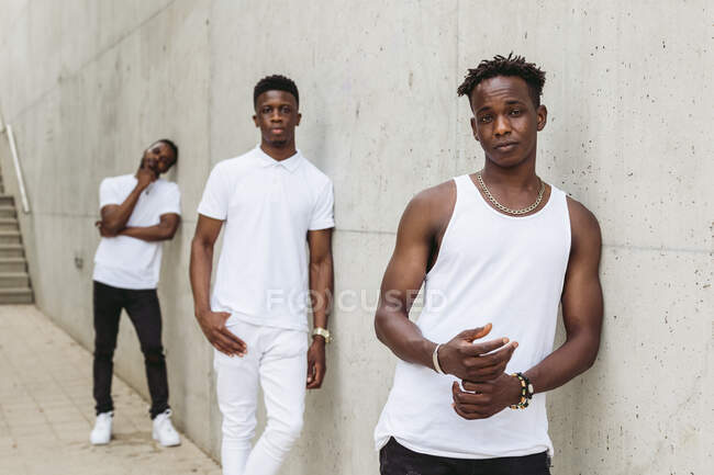 Cool afro-americanos amigos do sexo masculino vestindo roupas da moda com t-shirt branca de pé perto do edifício e olhando para a câmera — Fotografia de Stock