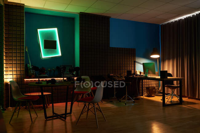 Interior de estudio oscuro para grabación de podcast con computadora moderna y micrófonos colocados en mesas - foto de stock