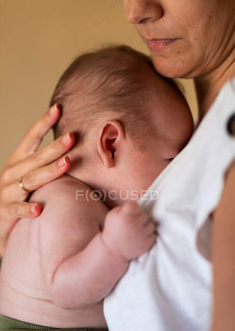 Vista laterale del raccolto calma giovane donna abbracciando e accarezzando adorabile bambino durante il giorno — Foto stock