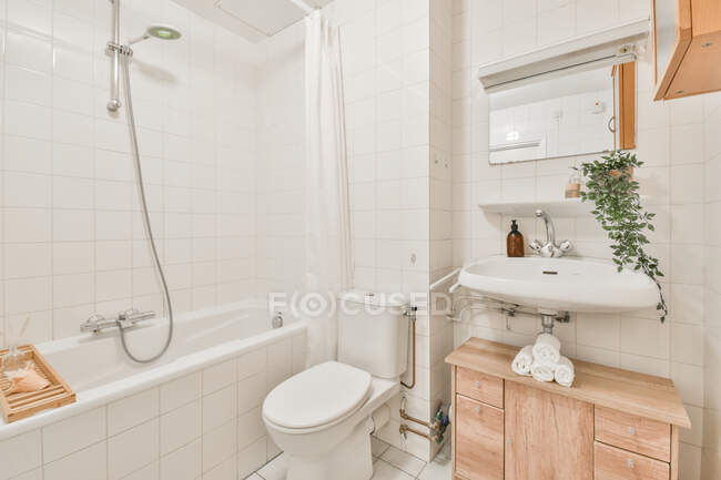 Просторная современная ванная комната с белой ванной и раковиной под зеркалом в новой квартире — стоковое фото
