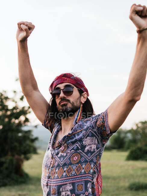 Hombre sin emociones con las manos levantadas y bandera lgtbi pintado en su cuello - foto de stock