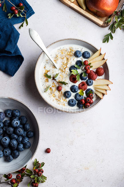 Top view bowl of delicious porridge topped with blueberries and raspberries near slices of pear served on table during breakfast — Stock Photo
