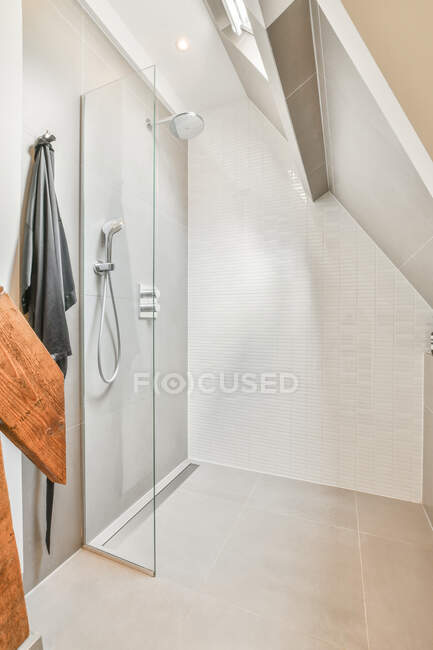 Интерьер современной минималистской ванной комнаты с душевой кабиной и черепичными стенами в мансарде в солнечный день — стоковое фото