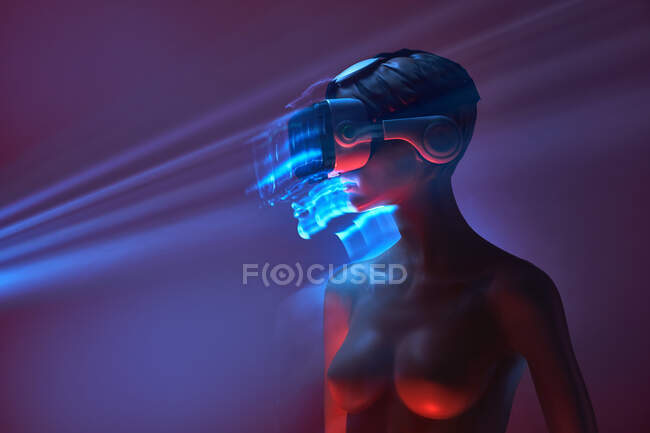 Frauenattrappe in futuristischer VR-Brille unter heller Projektion in schummrigem Raum platziert — Stockfoto