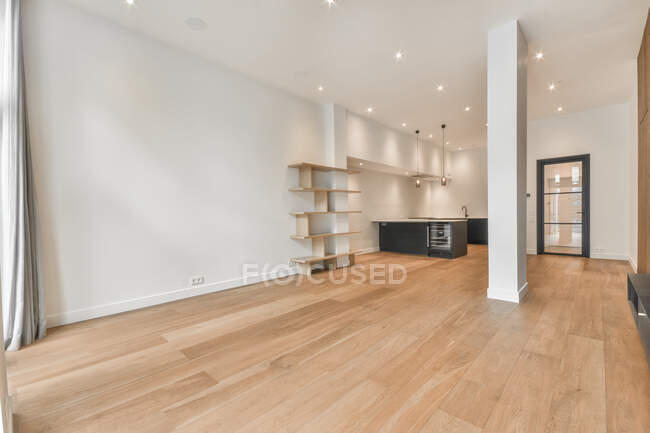 Interior de cozinha espaçosa com mobiliário preto minimalista em apartamento moderno com paredes brancas, piso em parquet de madeira e colunas — Fotografia de Stock