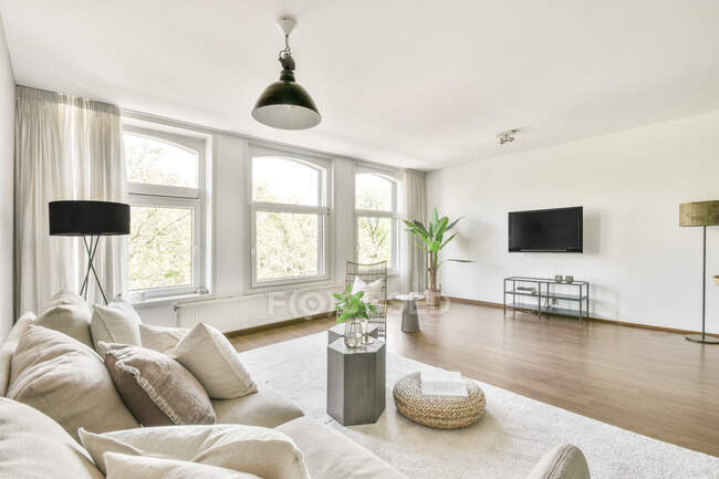 Интерьер просторной гостиной с серой мебелью и бежевым паркетным полом в квартире в минимальном стиле — стоковое фото