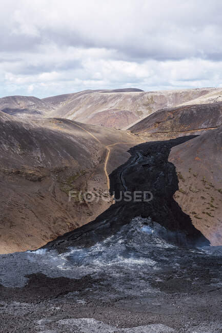 З верху мальовничого краєвиду активного вулкана Фаградальсфьялл з сухими чорними лавами, розташованими в Ісландії в денний час. — стокове фото