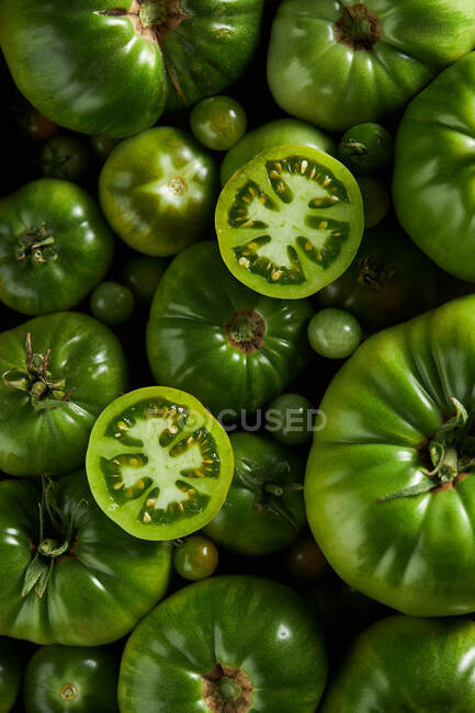 Top view of sliced of unripe berry of Solanum lycopersicum plant with scattered tomatoes — Stock Photo