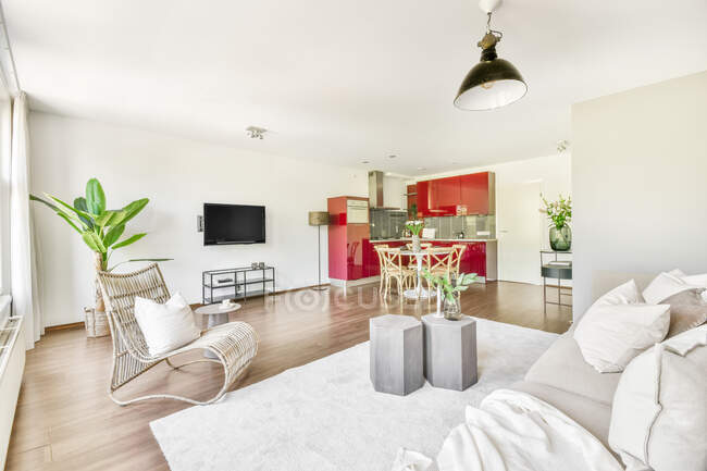 Wohnbereich mit bequemem Sofa und Sessel und Küche mit roten Möbeln in zeitgenössischer offener Wohnung — Stockfoto
