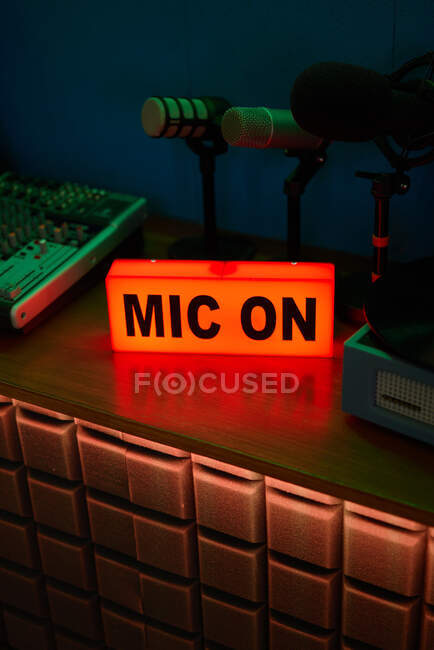 Microfone moderno em tripé colocado na mesa em estúdio escuro com iluminação de néon antes de gravar podcast — Fotografia de Stock