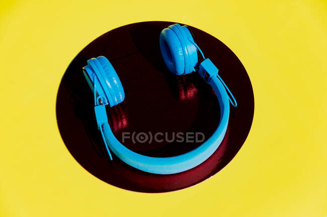 Top view of wireless headphone placed on circle on yellow background — Stock Photo